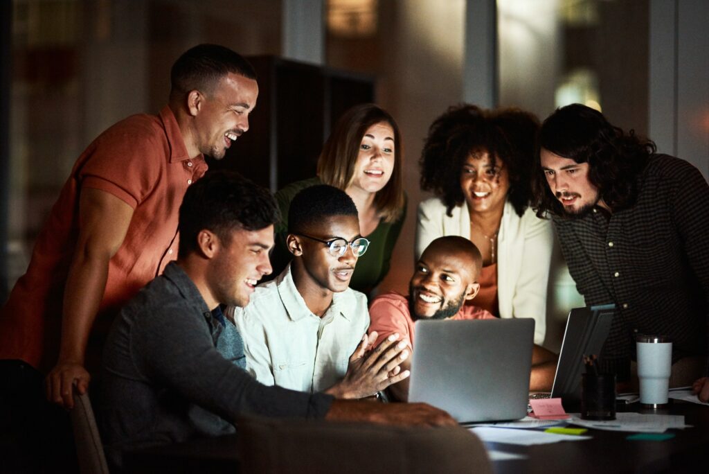 Shot of a group of designers looking at something on a laptop while working late